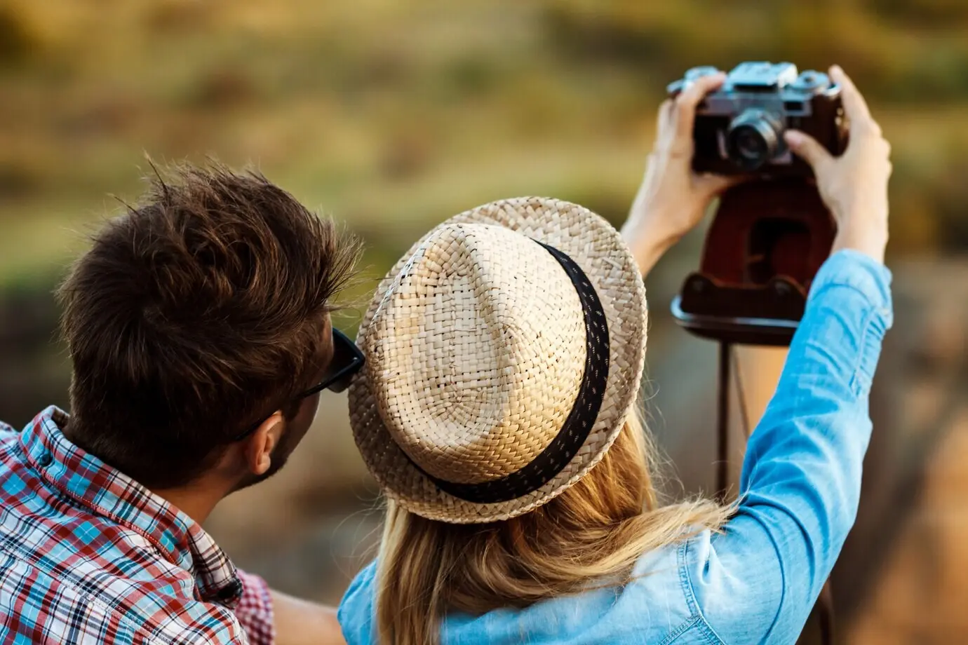 Junges, schönes Paar macht ein Selfie mit einer alten Kamera, im Hintergrund ein Canyon.
